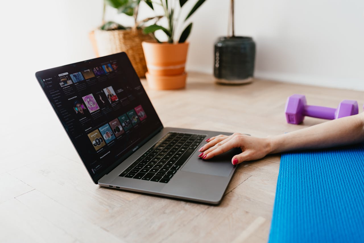 Hand of anonymous female on touchpad of laptop while surfing internet lying on mat at home during workout
